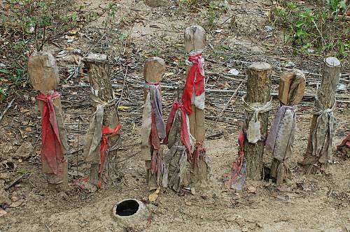 Strips of red colored cloths tied to wooden posts in the ground.