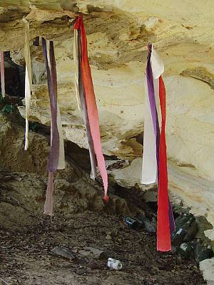 Strips of red cloth hanging from a cave ceiling.