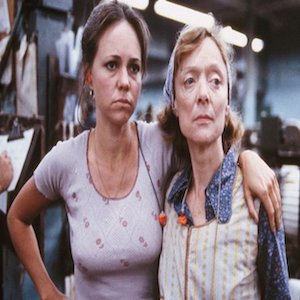 Film still shows two women in a factory. One (portrayed by Sally Field) has her arm around the other.