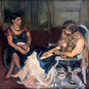 Two young women sit opposite each other, perhaps in conversation. The woman on the left is of Indian descent, and the woman on the right is of European descent.