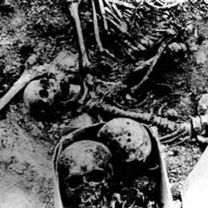 Black and white photograph of unearthed human skulls and bones