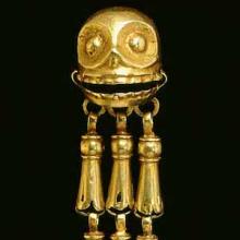 Gold earring featuring a skull with three dangles below it.